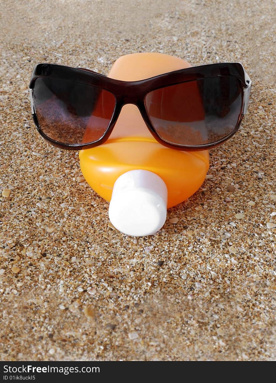 Antisun cream and antisun glasses on marine sand