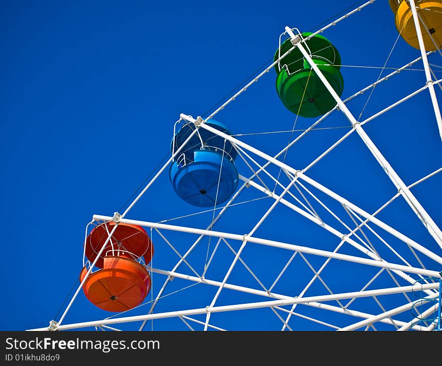 Fragment of wheel reviews with coloured cabins on background of blue sky