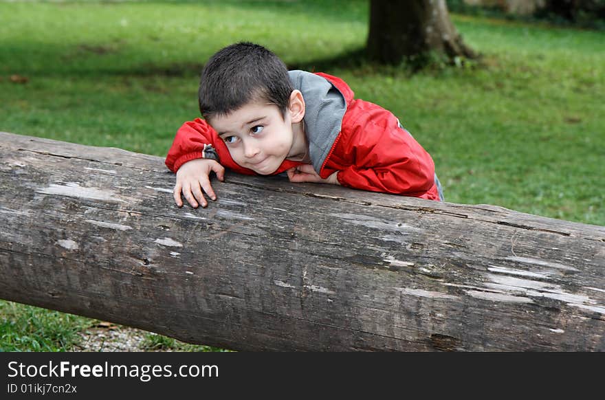 Boy With Sly Expression Leans On Log