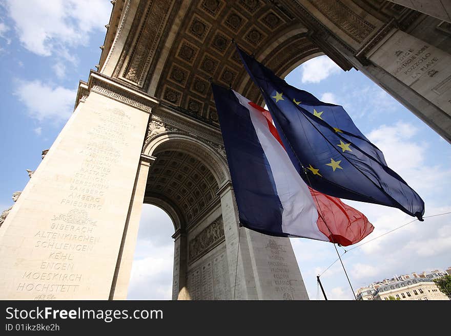 The flags of France and the European Union flying under the Arc de Triomphe in Paris, France. The flags of France and the European Union flying under the Arc de Triomphe in Paris, France.