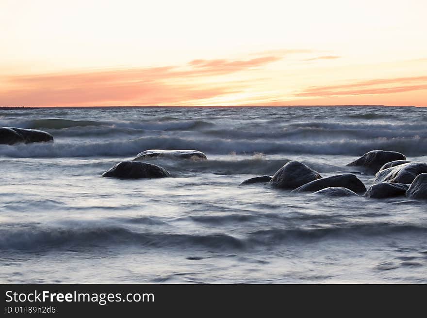 Sea at sunset, stones and soft waves