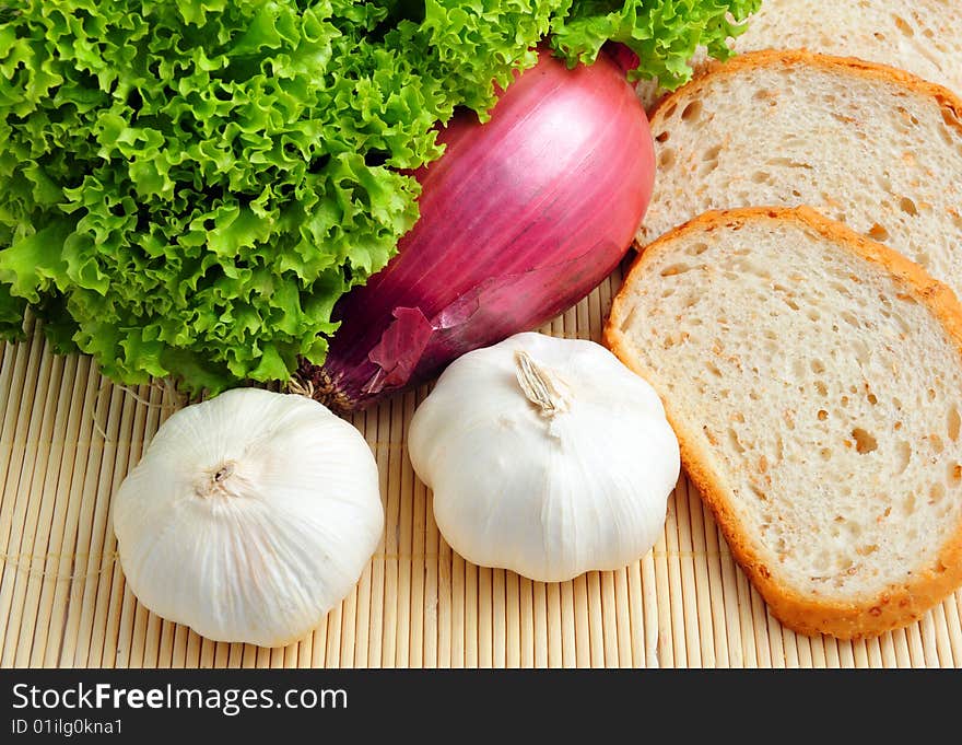 Salad, garlic, onion and bread on wooden background. Salad, garlic, onion and bread on wooden background