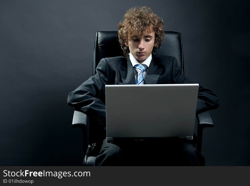 Young businessman standing on office chair and using laptop. Young businessman standing on office chair and using laptop