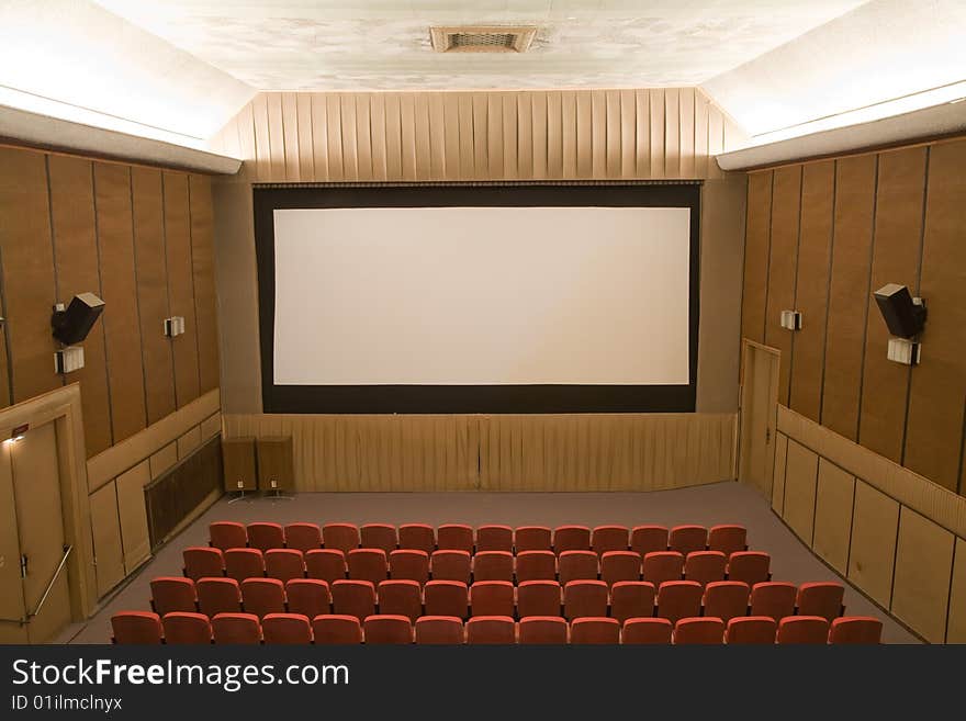 Old retro style cinema auditorium with line of red chairs and silver screen. Ready for adding your own picture. Old retro style cinema auditorium with line of red chairs and silver screen. Ready for adding your own picture.