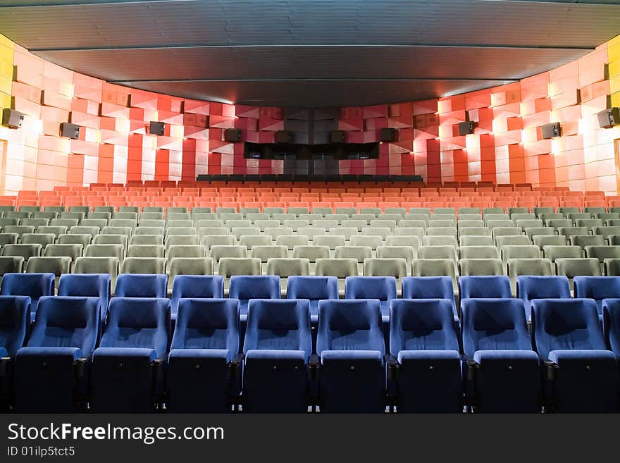 Empty new cinema auditorium with rows of blue, gray and red chairs. Empty new cinema auditorium with rows of blue, gray and red chairs.