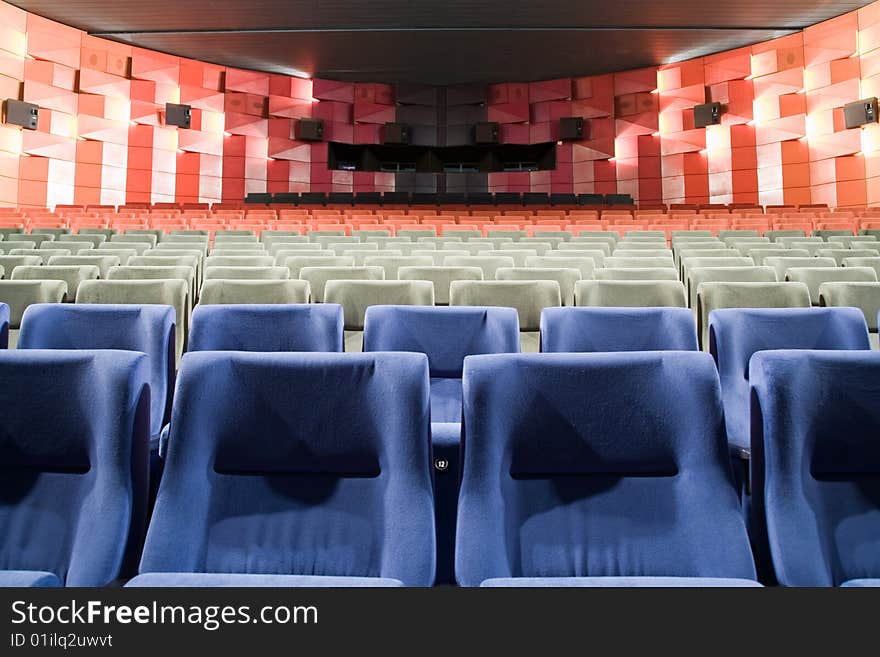 Empty new cinema auditorium with rows of blue, gray and red chairs. Empty new cinema auditorium with rows of blue, gray and red chairs.