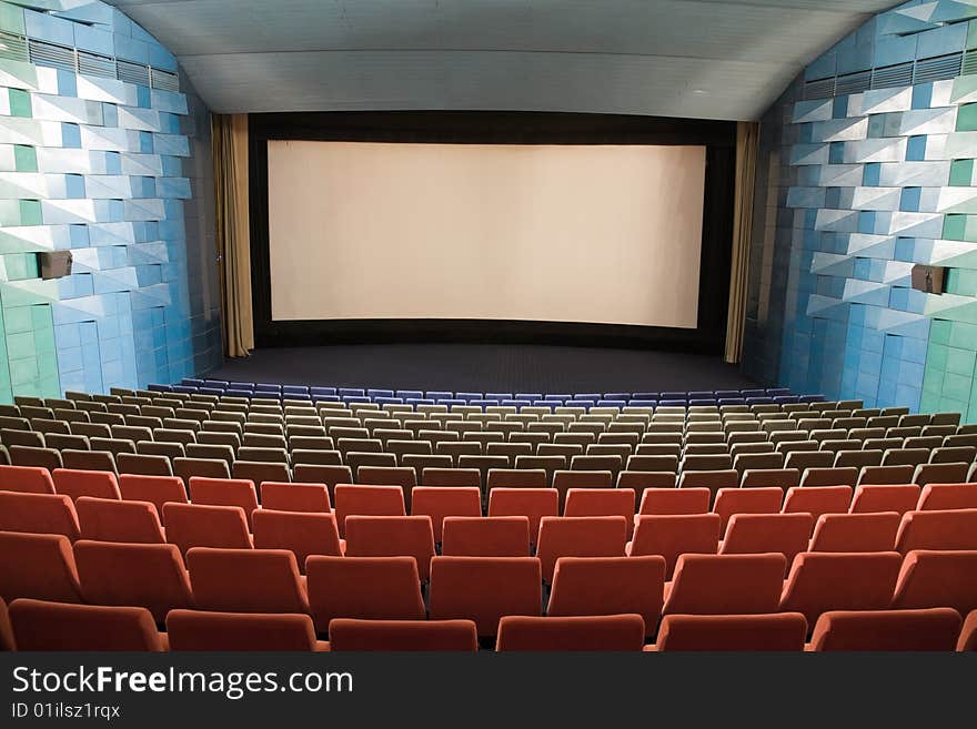 Empty cinema auditorium with line of chairs and stage with silver screen. Ready for adding your own picture. Empty cinema auditorium with line of chairs and stage with silver screen. Ready for adding your own picture.