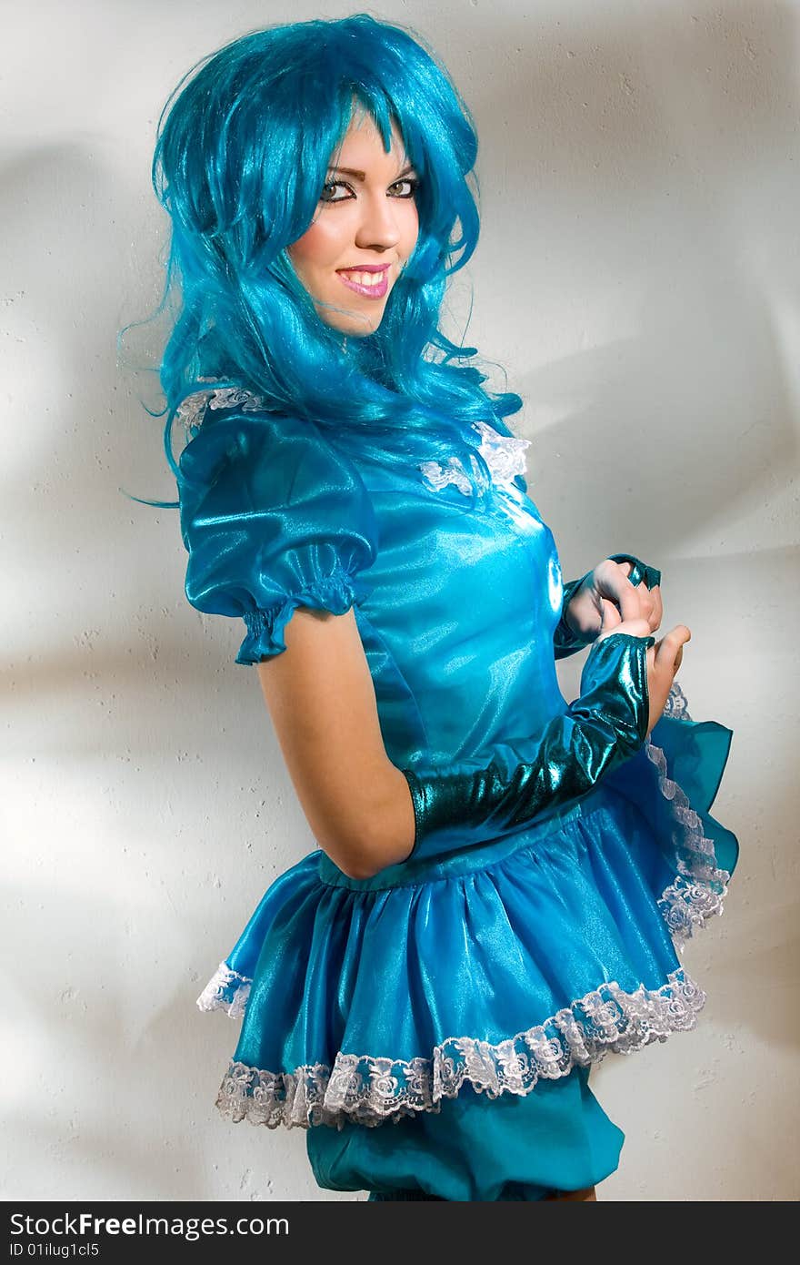 Woman wearing blue dress and wig against the wall with fancy light pattern