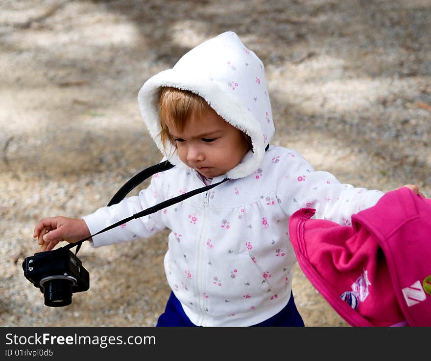 A young girl running with a compact digital camera and a red jacket in hand. A young girl running with a compact digital camera and a red jacket in hand