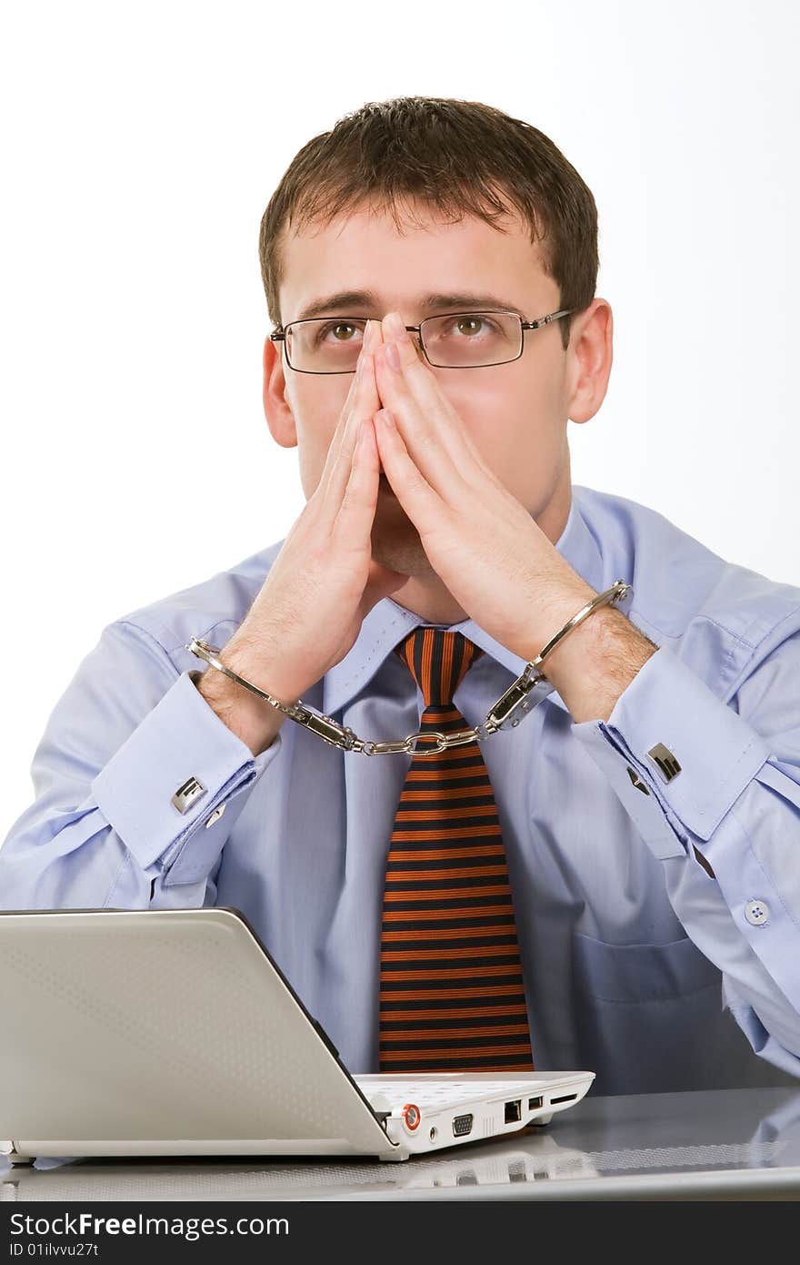 Handsome young businessman bound to laptop with handcuffs. Handsome young businessman bound to laptop with handcuffs