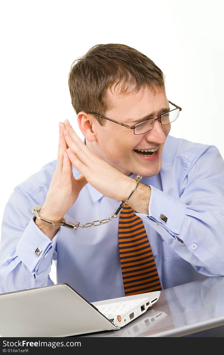 Handsome young businessman bound to laptop with handcuffs. Handsome young businessman bound to laptop with handcuffs