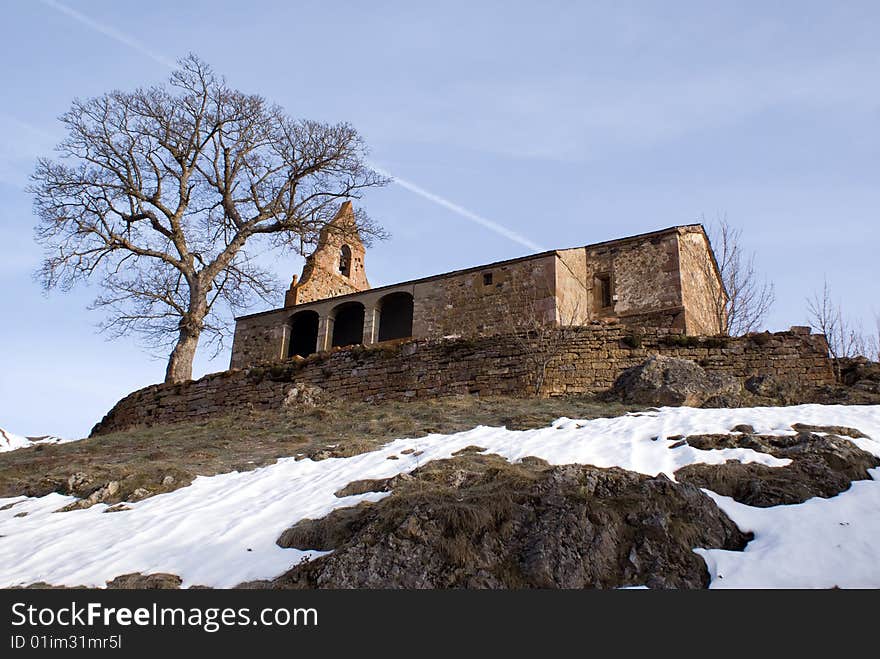 Stone chapel next to tree.