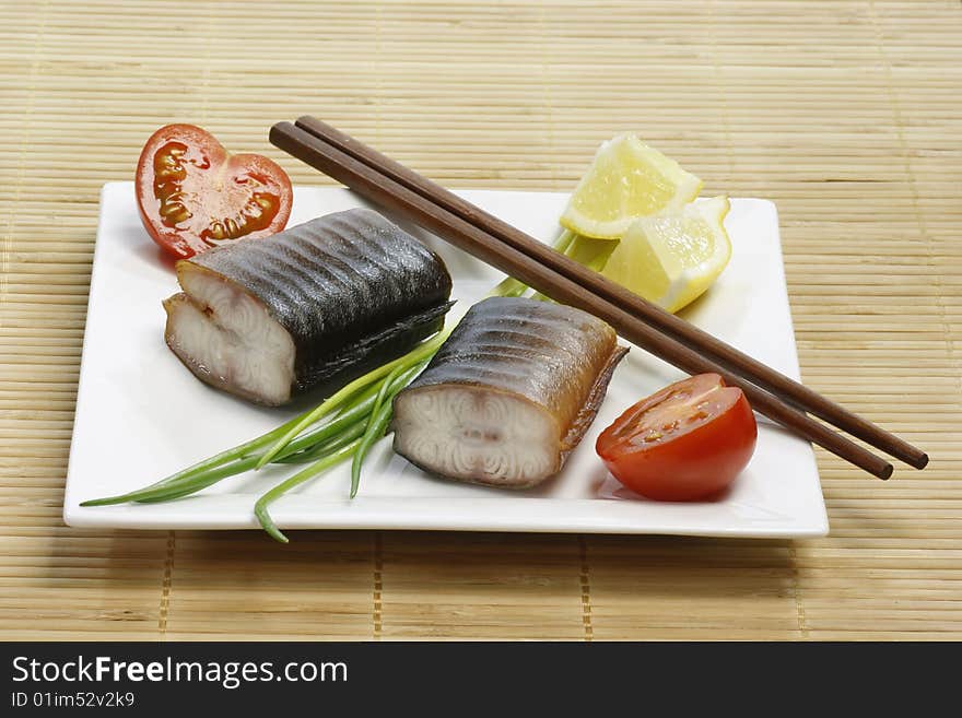 Pieces of smoked eel on a plate with garnish. Pieces of smoked eel on a plate with garnish