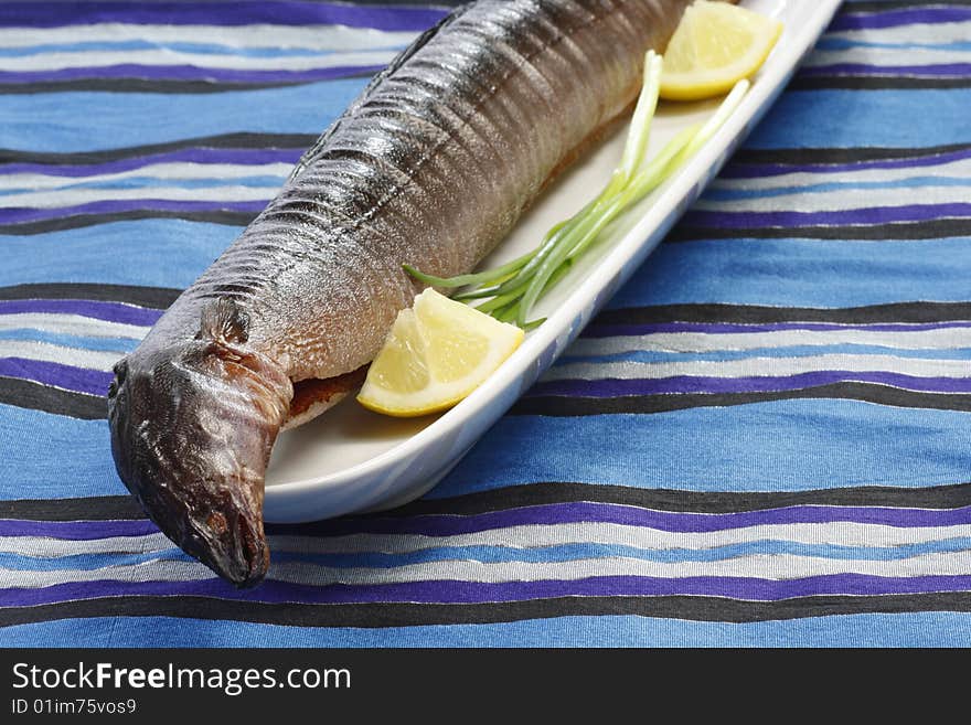 Whole smoked eel with garnish on a plate