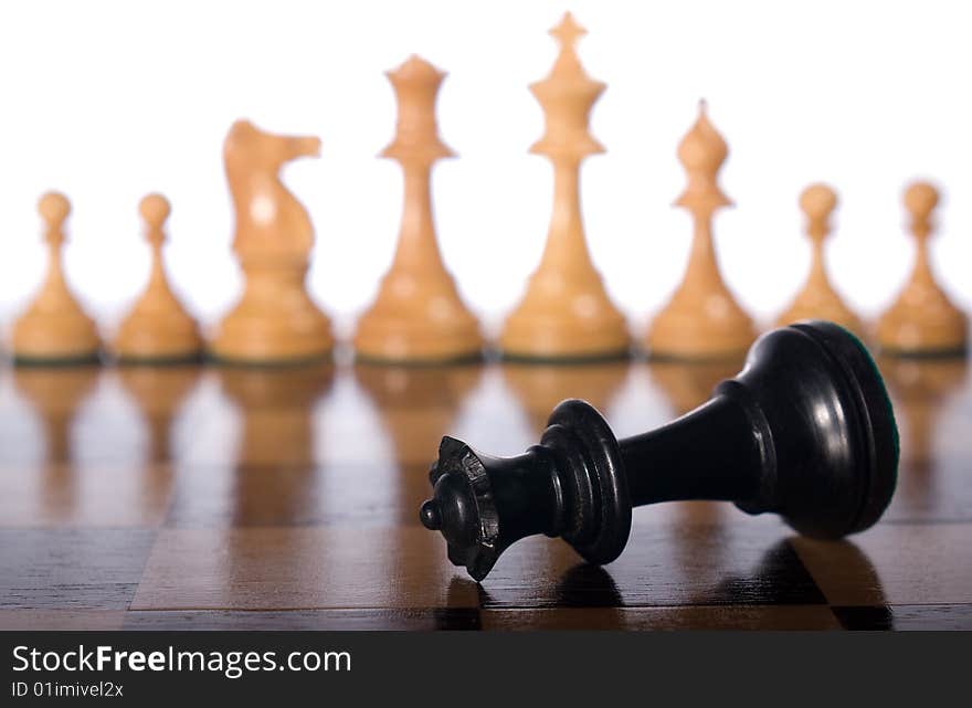 Chess queen on a chessboard as a business concept with out of focus chessmen. Chess queen on a chessboard as a business concept with out of focus chessmen