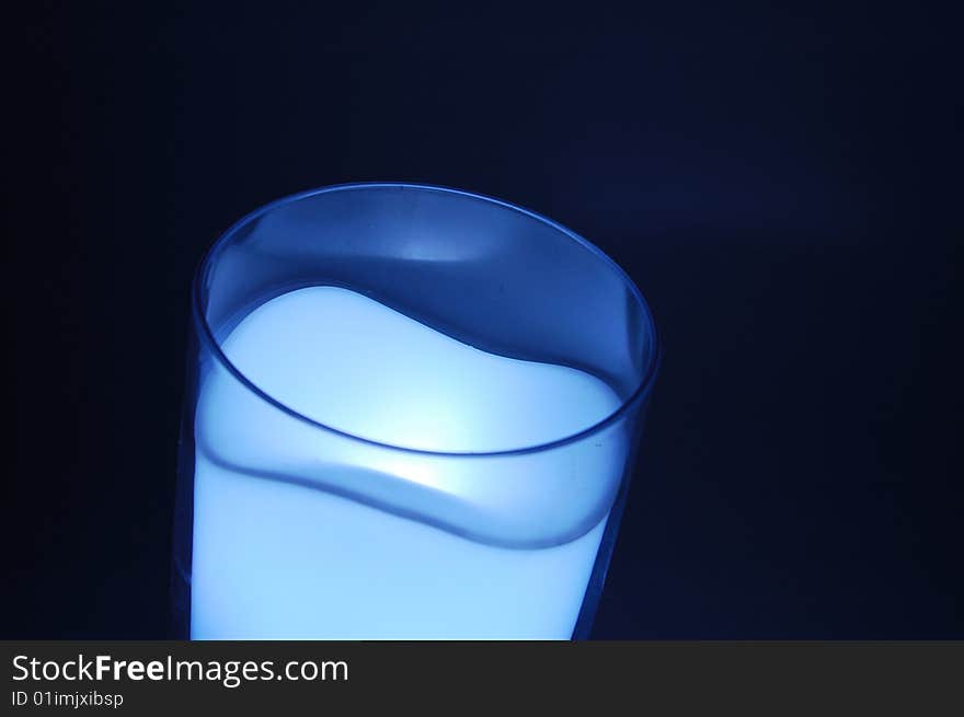 Cup filled with milk mapping under the lights in the background