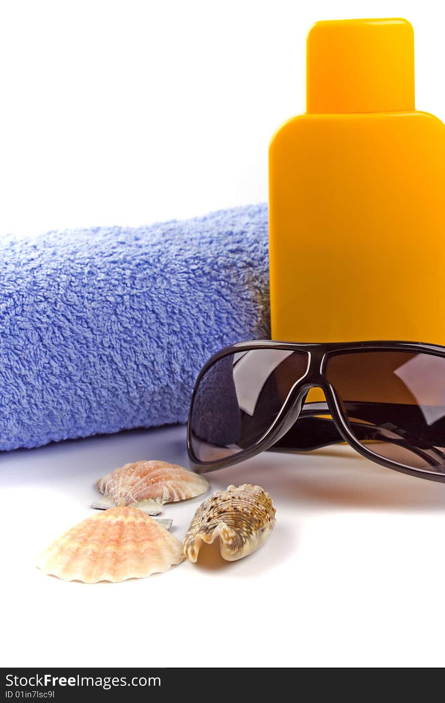 Towel, sunglasses and lotion closeup on white background