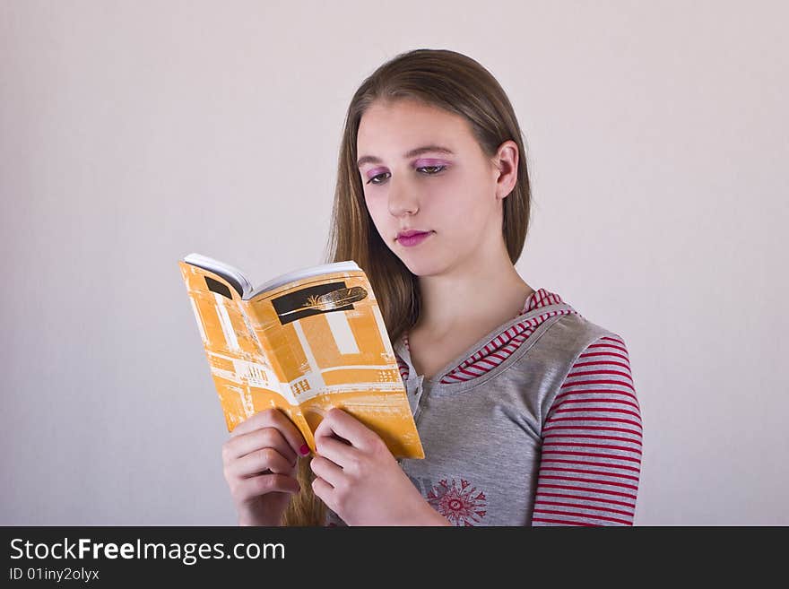 Teenage girl holding and reading Book, over gray background. Teenage girl holding and reading Book, over gray background.