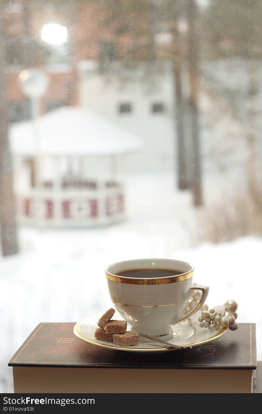 Porcelain cup with coffee on a stack of books by the window. Porcelain cup with coffee on a stack of books by the window