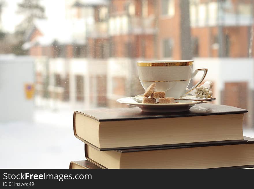 Porcelain cup with coffee on a stack of books by the window. Porcelain cup with coffee on a stack of books by the window