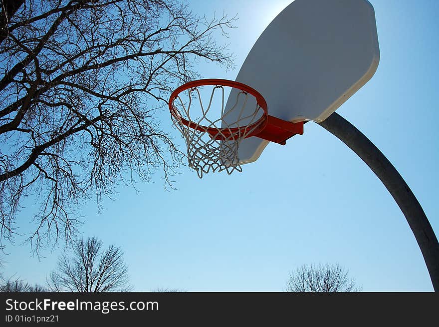 An image of a basketball hoop under the sun.