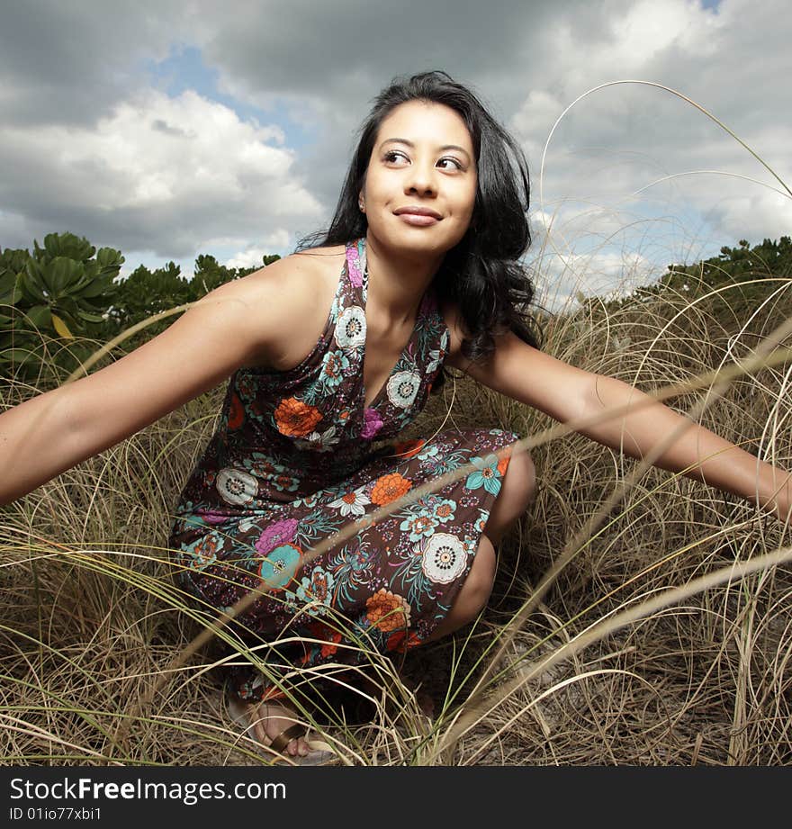 Young woman squatting down in a field of dunes. Young woman squatting down in a field of dunes