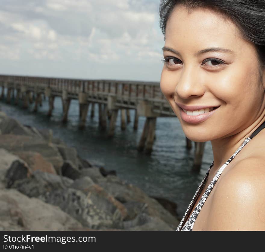 Woman smiling with a rock formation and pier in the background. Woman smiling with a rock formation and pier in the background