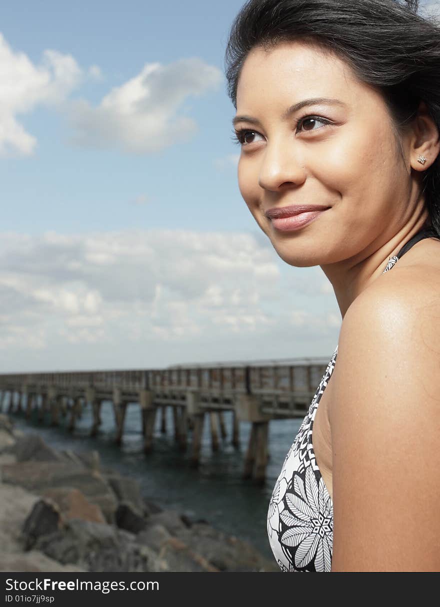 Woman smiling with a rock formation and pier in the background. Woman smiling with a rock formation and pier in the background