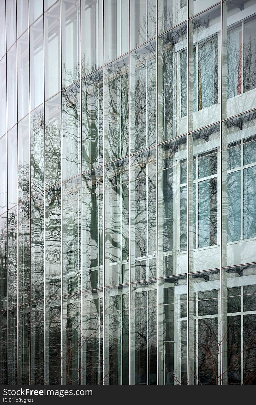 Office building facade, with trees reflected in the glass.