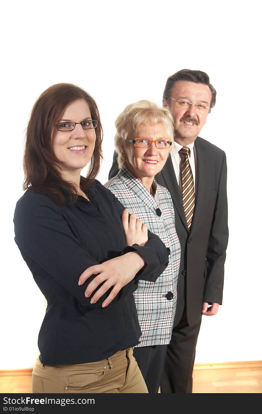 Small group of business people in business suits standing looking forward. Focus is on the young woman in front. Small group of business people in business suits standing looking forward. Focus is on the young woman in front.