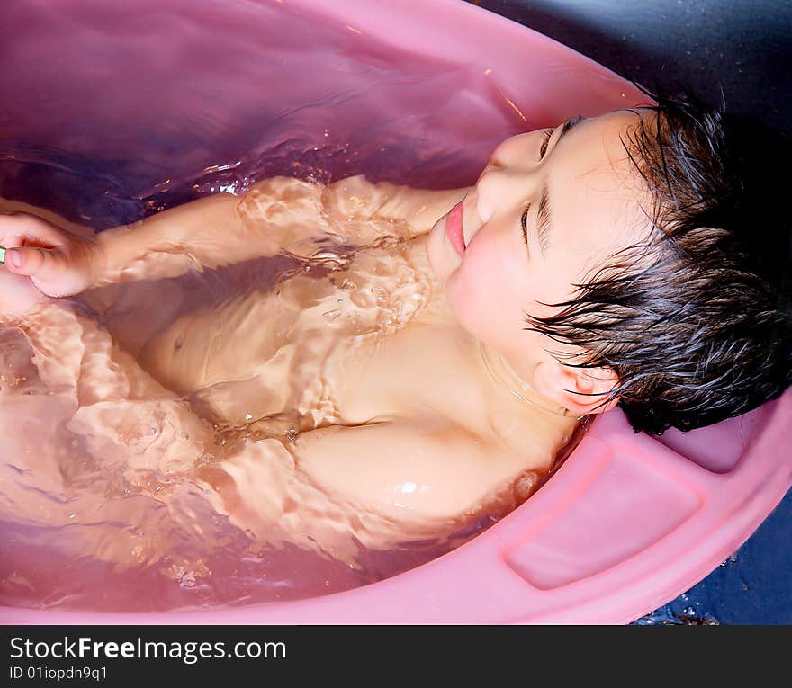 A picture of a little chinese boy taking bath and playing with water happily. A picture of a little chinese boy taking bath and playing with water happily