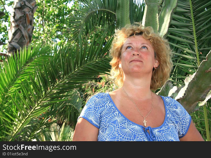 Pretty blond woman in tropical park.