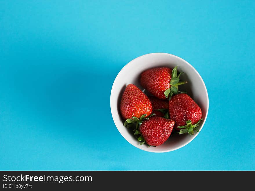 Bowl of strawberries on clear blue background