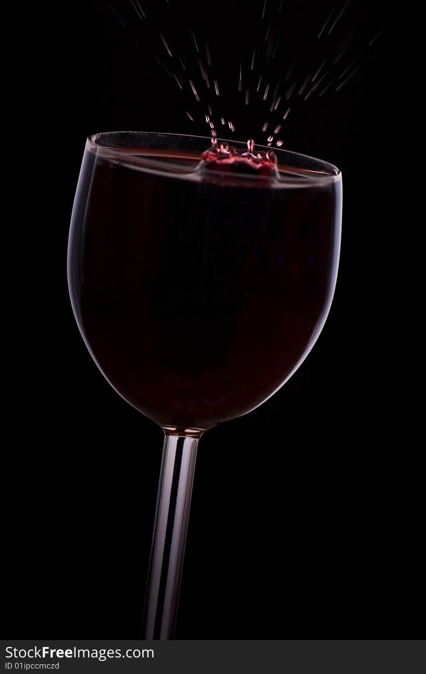 A drop of red wine falls into the glass