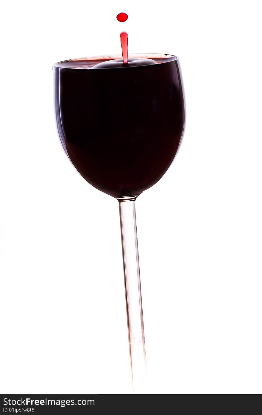 A drop of red wine falls into the glass