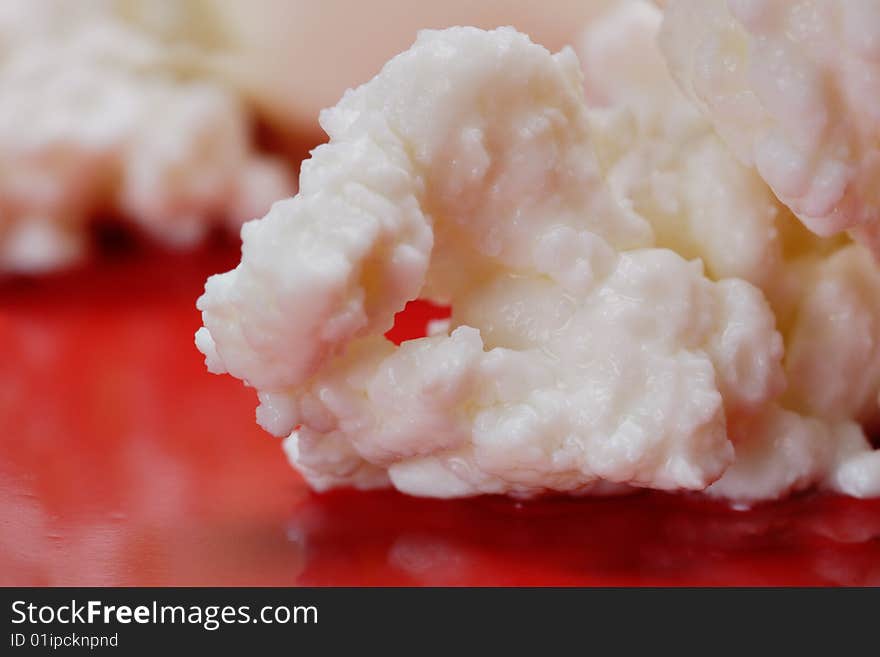 Cottage cheese on the red plate. Close-up. Narrow depth of field. Cottage cheese on the red plate. Close-up. Narrow depth of field.