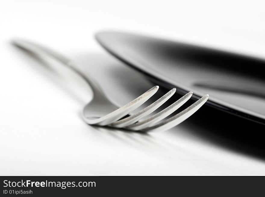 Fork and black plate on white background. Fork and black plate on white background