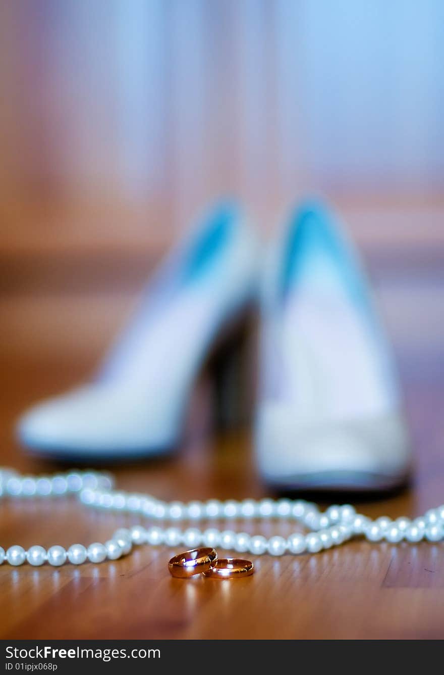 Beautiful wedding background with shoes, beads and gold rings (shallow DOF)