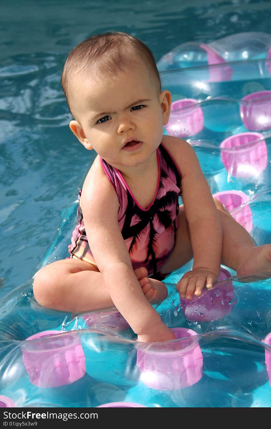 Curious baby sitting on an inflatable raft in a swimming pool. Curious baby sitting on an inflatable raft in a swimming pool