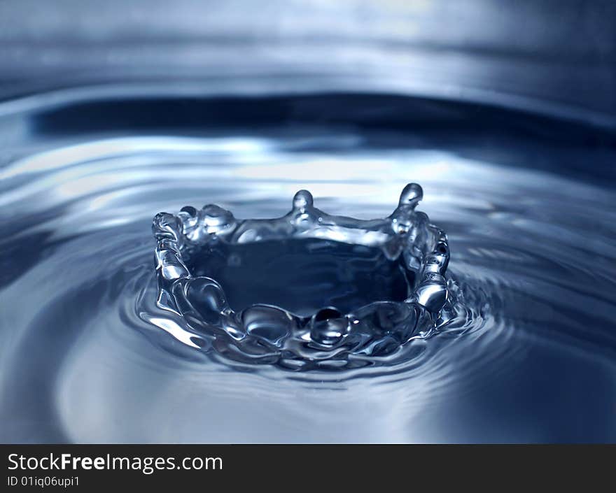 Drop splash in a form of crown on blue water surface