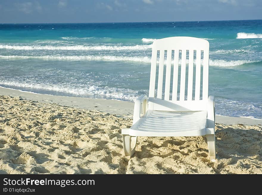 White plastic long chair on a sandy beach