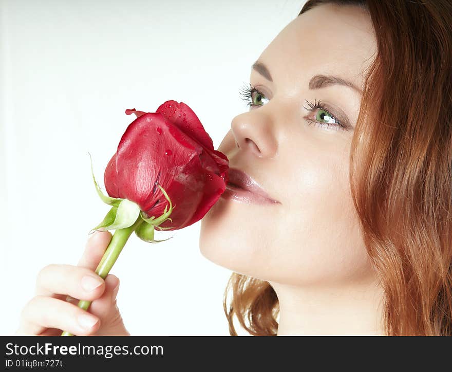 Beautiful woman inhales aroma of a rose