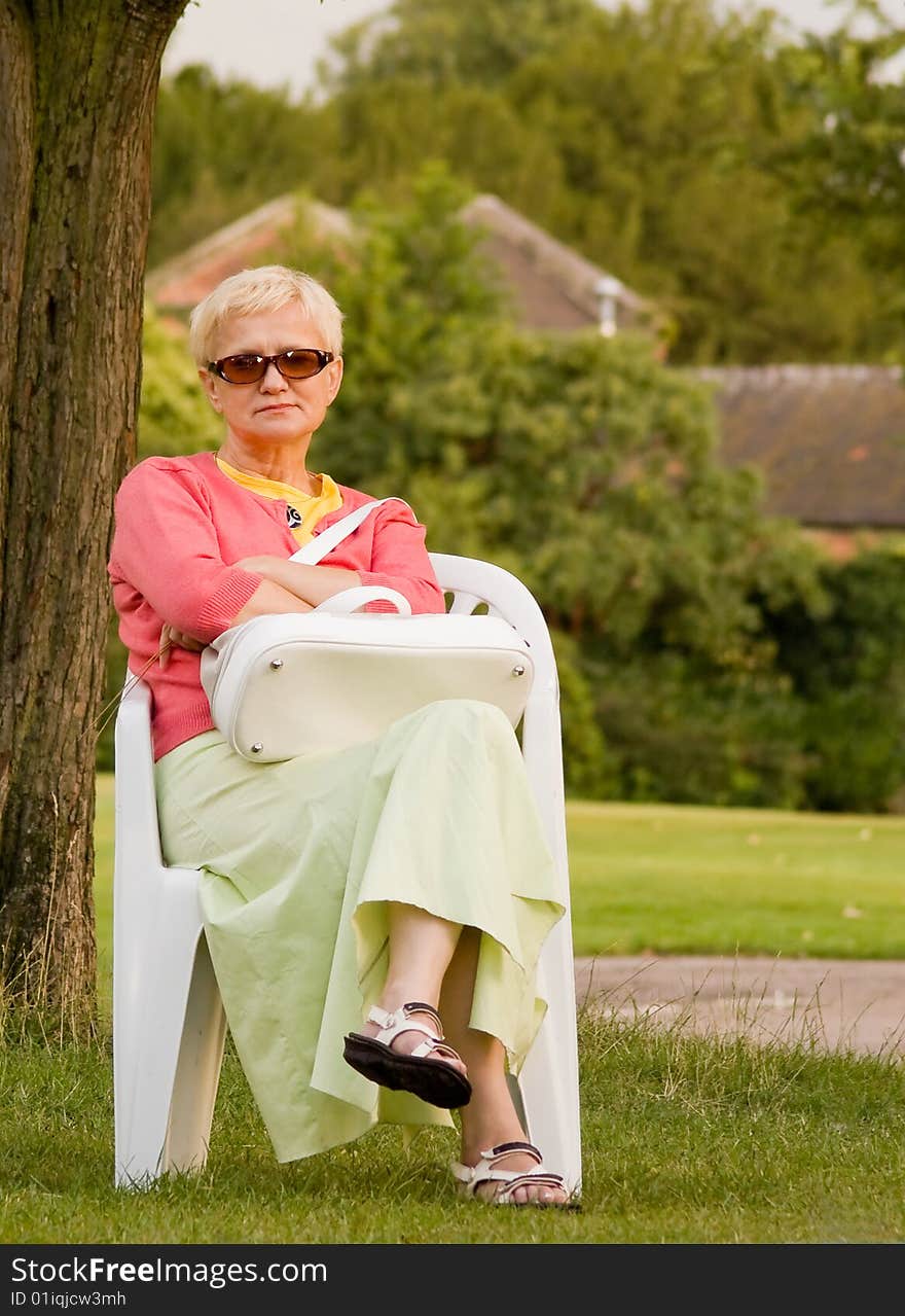 Woman sitting on the chair; evening in the garden. Woman sitting on the chair; evening in the garden.