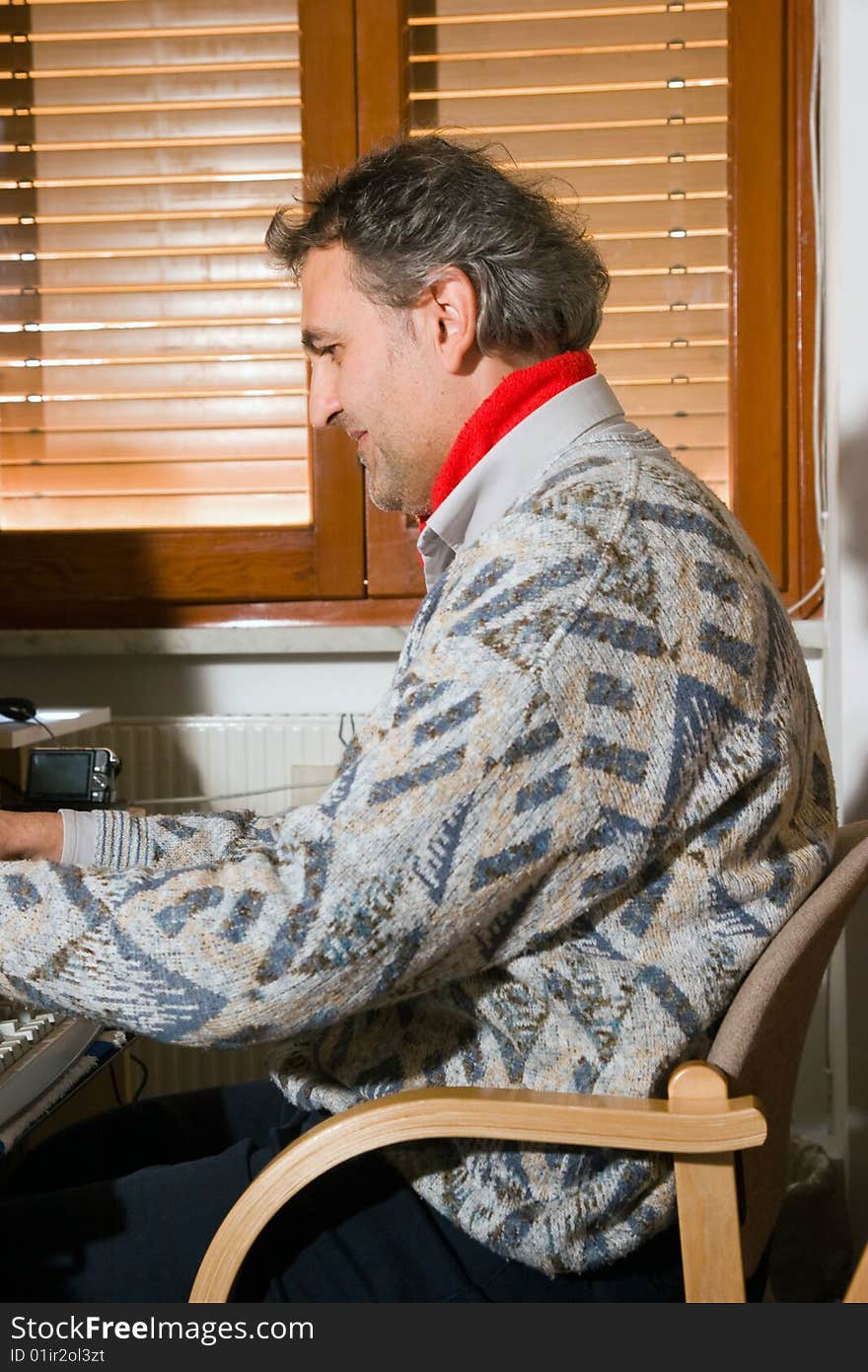 An elderly man at work with his computer at home