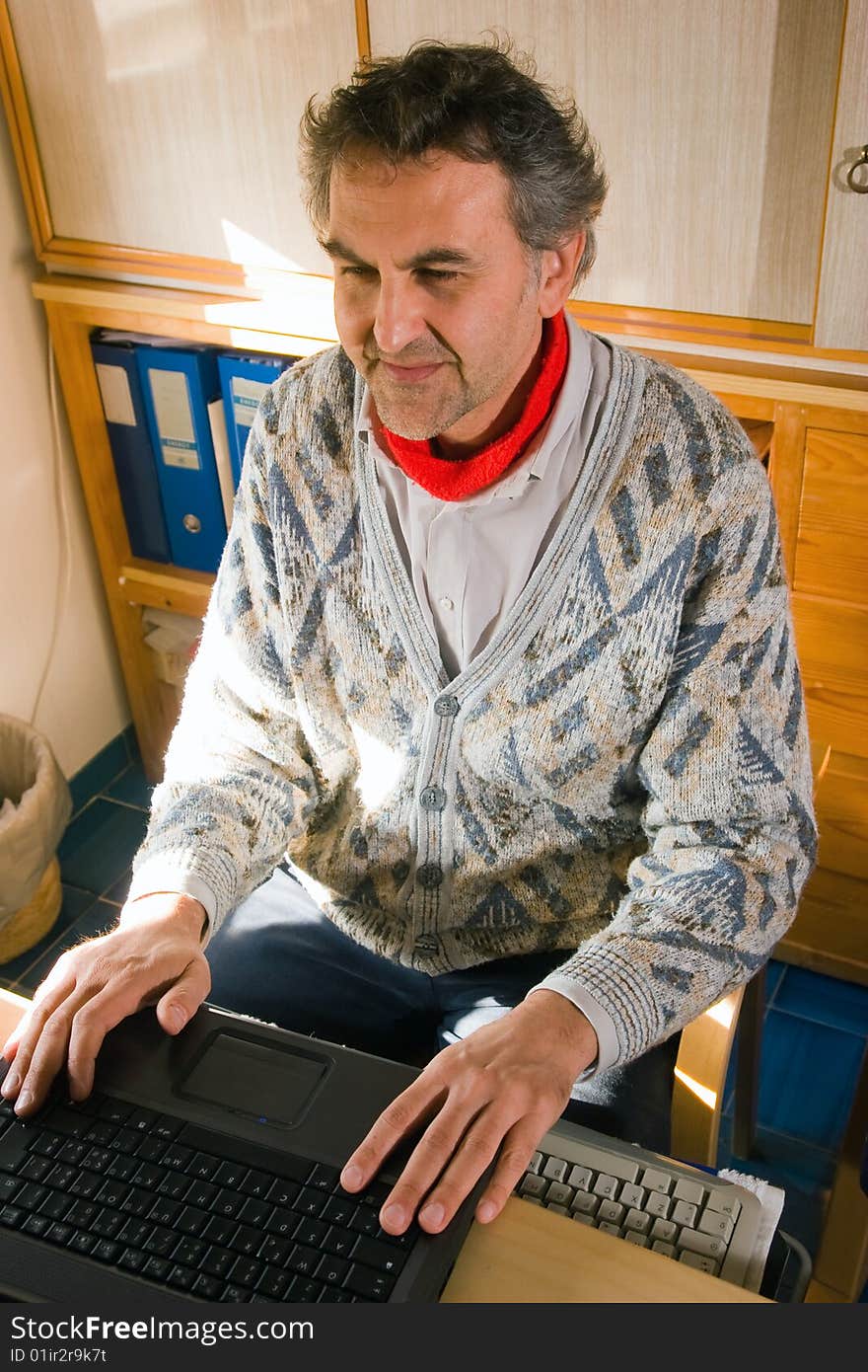 An elderly man at work with his computer at home