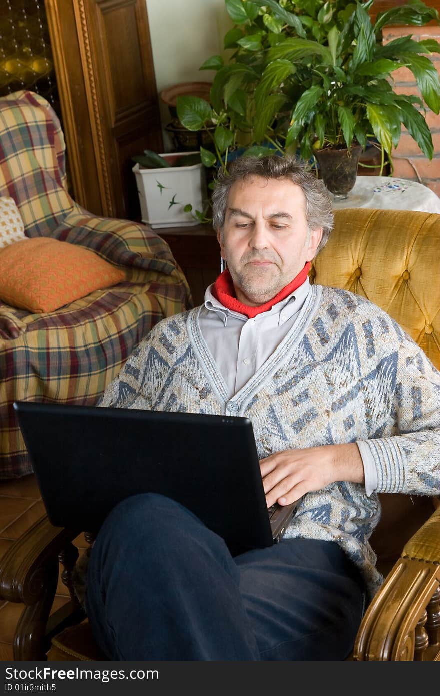 An elderly man at work with his computer at home