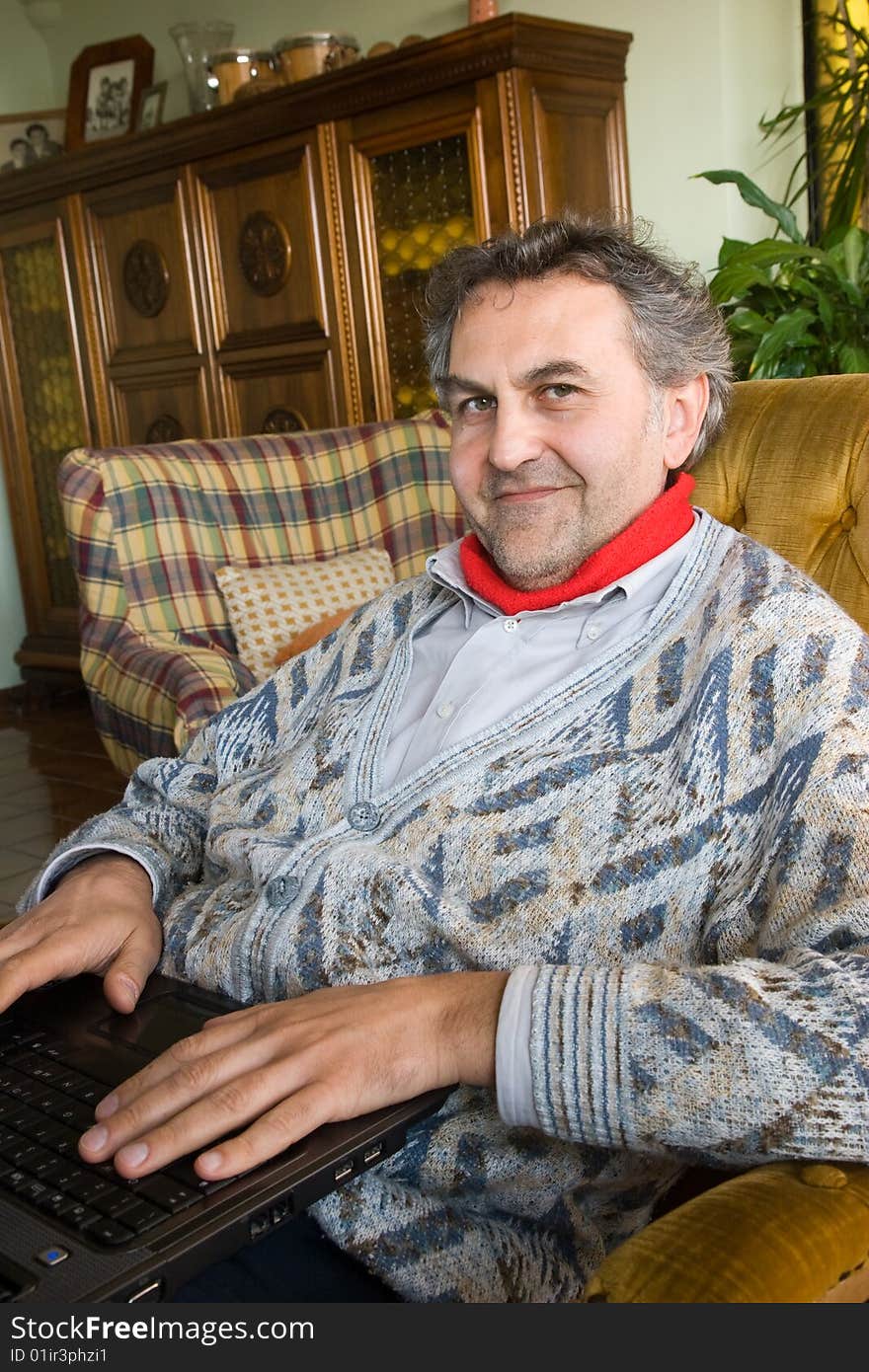 An elderly man at work with his computer at home