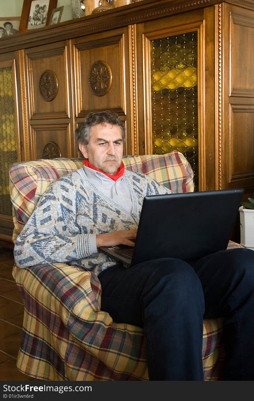 An elderly man at work with his computer at home