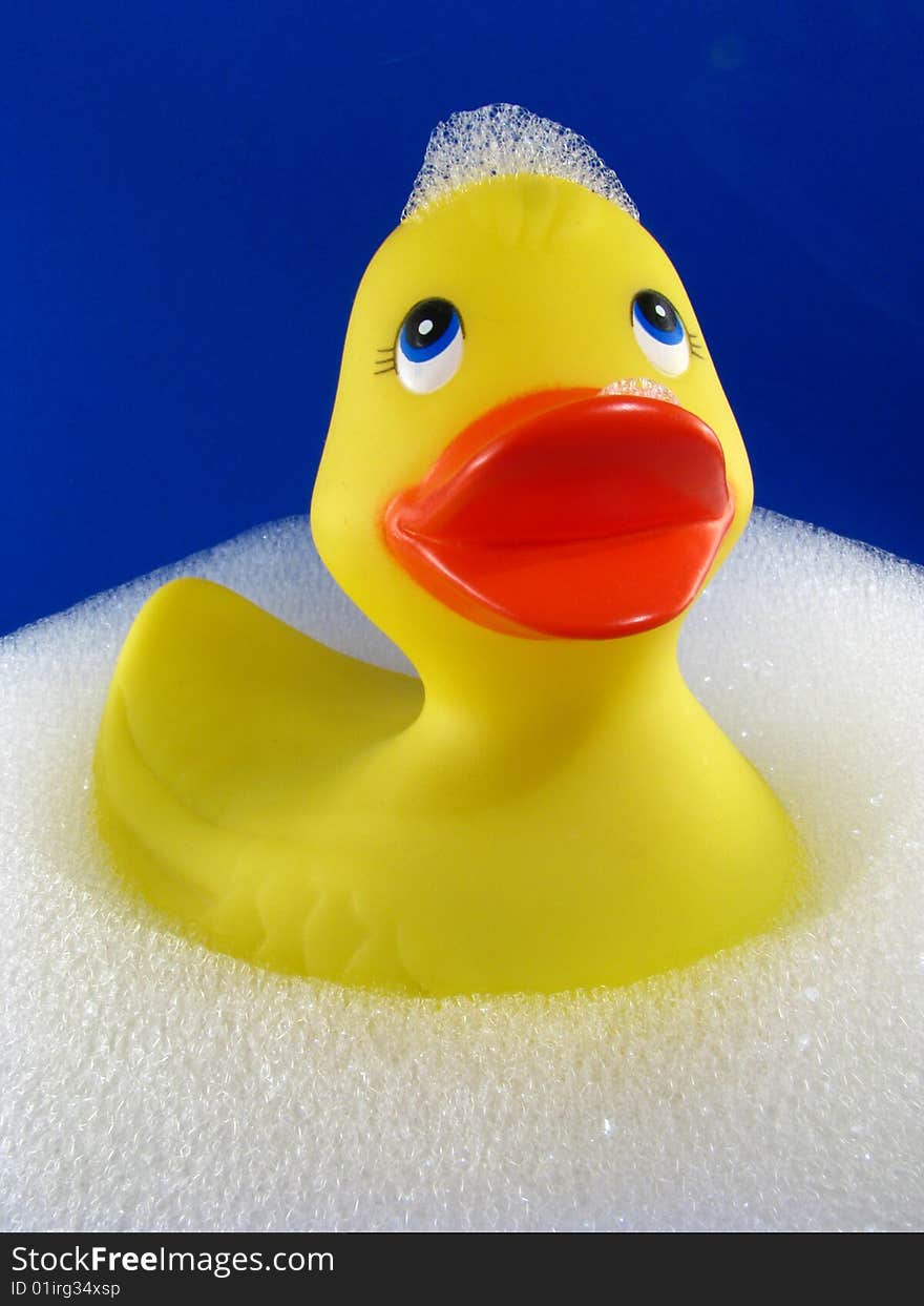 A rubber ducky floating in a bubble bath with a blue background. A rubber ducky floating in a bubble bath with a blue background