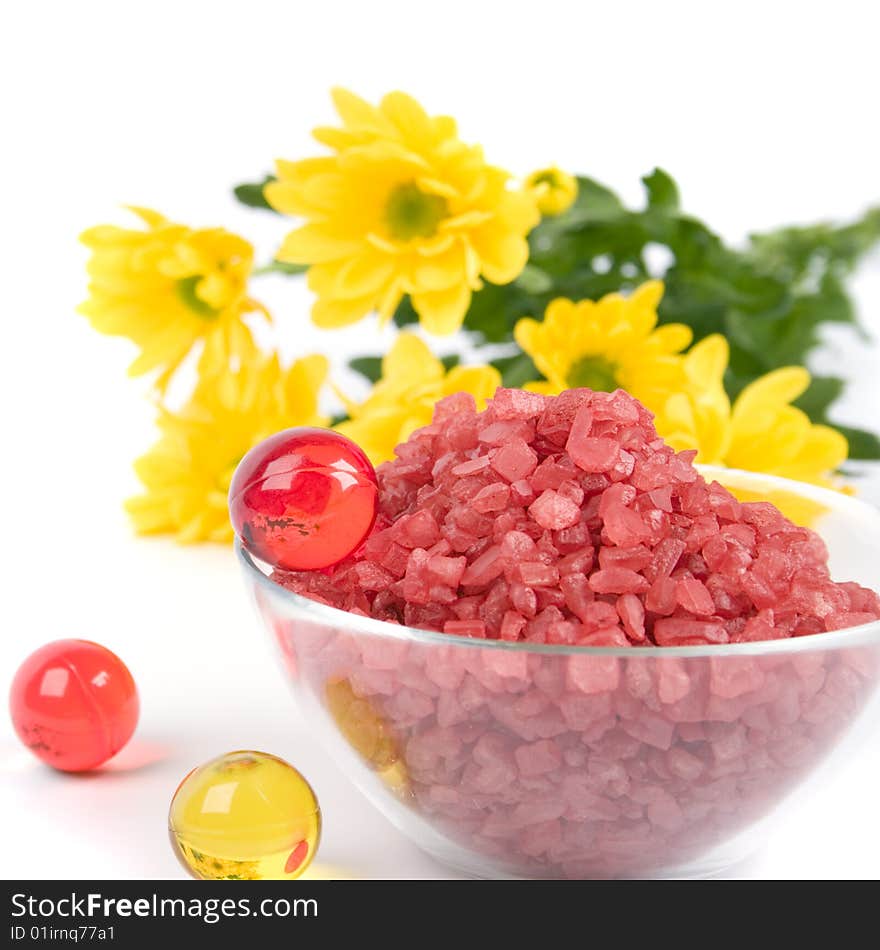 Spa products: bath salt, oil balls in a bowl and yellow flowers